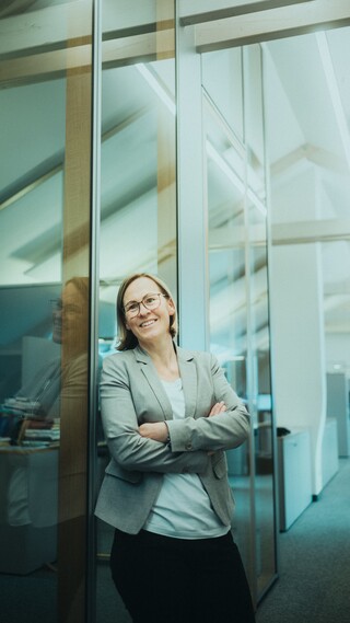 Frau lächelt und lehnt sich an den Türrahmen