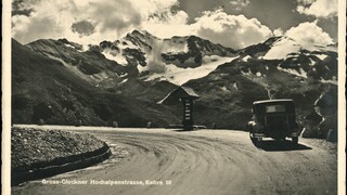 Ein altes schwarz-weiß-Foto zeigt ein Auto auf einer Straße mit Blick auf einen Gletscher.