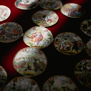 Schraubmünzen von oben fotografiert, die farbenfrohen Motive der Salzburger Protestantenbewegung sind gut erkennbar.