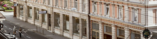 Stammhaus des Bankhaus Spängler in der Schwarzstraße 1 in 5020 Salzburg von außen. Die Fassade ist hellrosa, auffällig ist das Kuppeldach. Im Hintergrund sieht man die Festung Hohensalzburg sowie die Kuppeln des Salzburger Doms. 