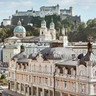 Stammhaus des Bankhaus Spängler in der Schwarzstraße 1 in 5020 Salzburg von außen. Die Fassade ist hellrosa, auffällig ist das Kuppeldach. Im Hintergrund sieht man die Festung Hohensalzburg sowie die Kuppeln des Salzburger Doms. 