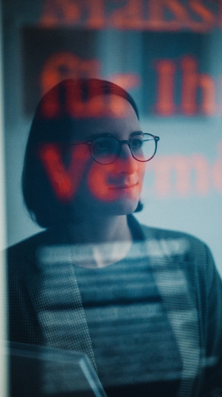Kurzhaarige Frau mit Brille schaut aus dem Fenster.