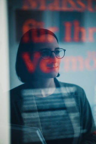 Kurzhaarige Frau mit Brille schaut aus dem Fenster.