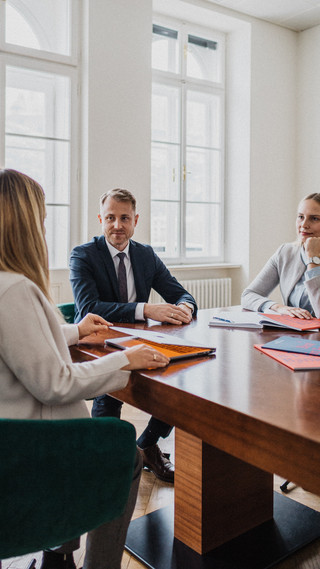 Drei Personen sitzen an einem Tisch und besprechen etwas.