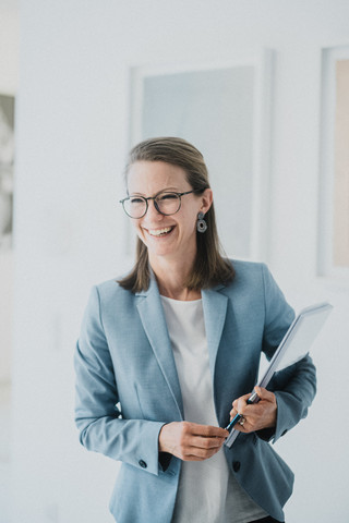 Eine Frau mit kurzen Haaren und Brille lacht freundlich.