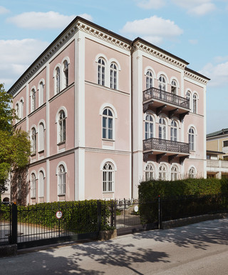 Bankgebäude des Bankhaus Spängler in der Schwarzstraße 17 in 5020 Salzburg von außen. Das Gebäude hat 3 Stockwerke, die Fassade ist hellrosa, 2 Balkone und viele Fenster sind ersichtlich. 