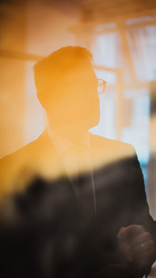 Ein Herr in Geschäftskleidung spiegelt sich in einem Gemälde.