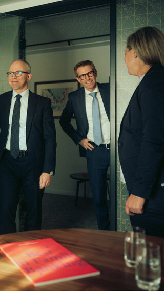 Vier Personen stehen im Meetingraum und blicken sich an.